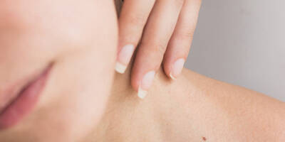 Woman applying neck cream to skin