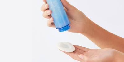 Woman showing how much makeup remover to dispense on a cotton pad