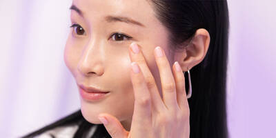 Woman showing how to apply a face serum with ferulic acid on to skin.