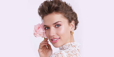 Woman with hair in updo wearing pretty soft natural makeup for wedding day.