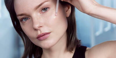 Woman applying Advanced Genifique face serum with a dropper