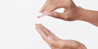 Hands with a pea sized amount of face primer on a spatula