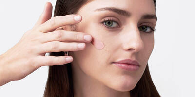 Woman with textured skin and large pores applying blurring face primer