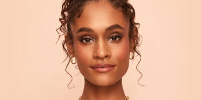 Warm brown smokey eye look and bronzed skin worn on a model with dark skin tone