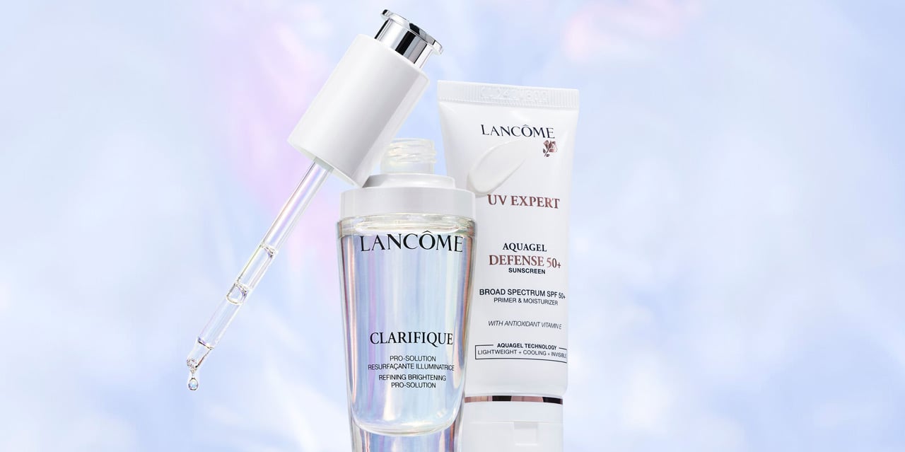 Tube of sunscreen and dark spot serum on a cloudy background